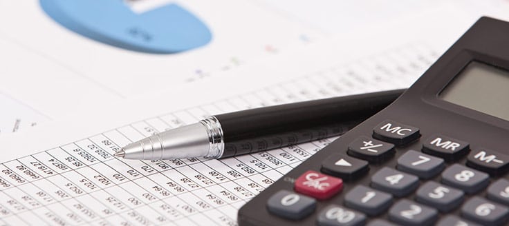 A pen and a calculator are placed on top of accounting sheets. Knowing the 10 basic accounting principles will help you create your small business’s financial statements.
