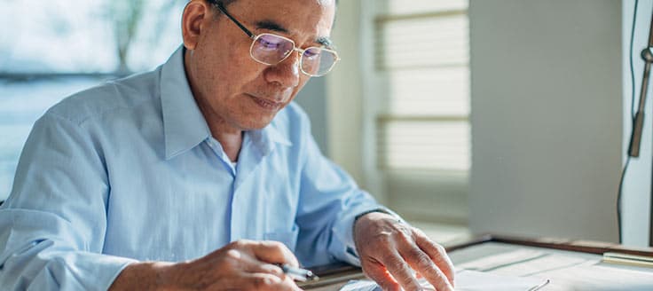A man works at his desk, possibly reviewing the information for his balance sheet.