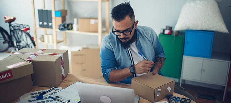 A man writes on a package he’ll ship to a customer. Lessons from an online business course might have helped him improve his ecommerce business.