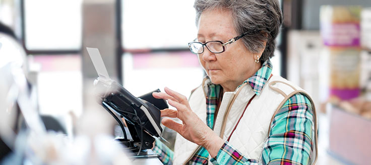 Woman paying at cashier register with a credit card.
