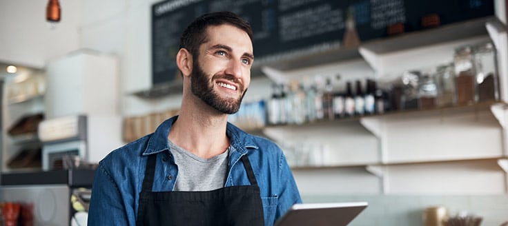 A cafe owner works on his tablet. Yelp has an app for business owners so you can access your listing across several devices.