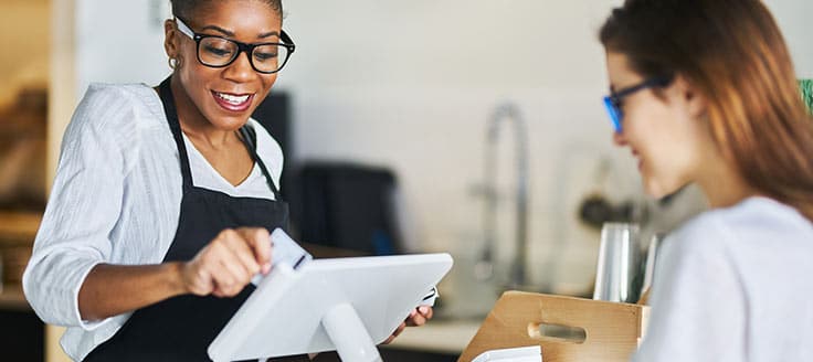 A business owner slides a customer's credit card through the payment processor on her tablet.