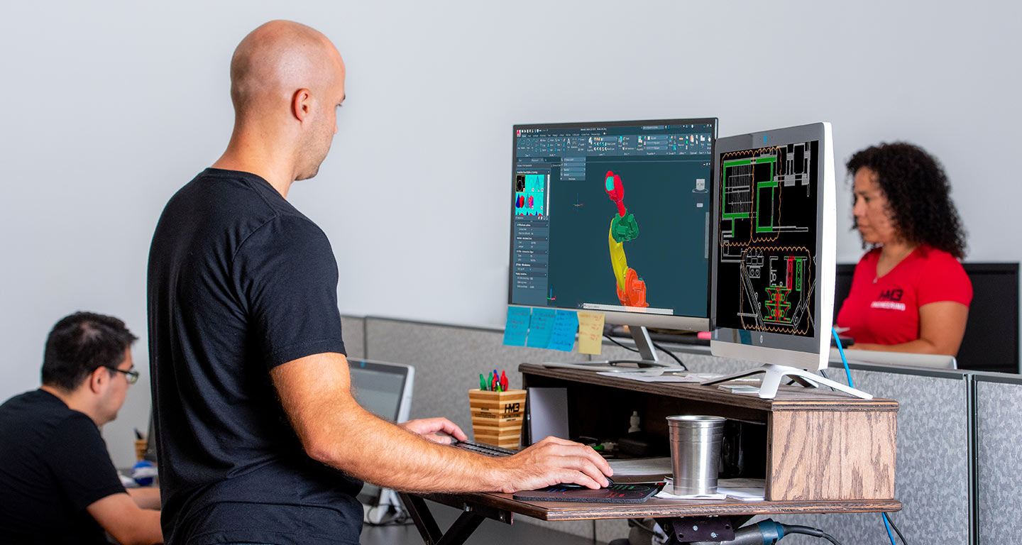 Employees of HM3 Engineering sitting before a computer screen.