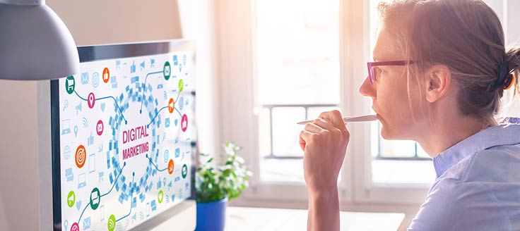A woman views a desktop screen that reads “digital marketing” as she plans her digital marketing schedule.