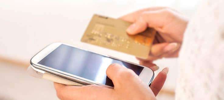 A woman enters her credit card information as she completes set up for recurring payments through an app or mobile site on her smartphone.