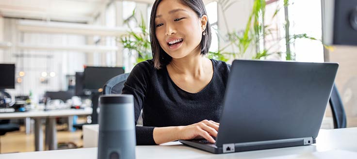 A woman talks to her virtual assistant while she works. AI and machine learning are on trend to impact the 2020 economy.