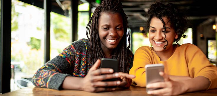 Two females check out content on their phones.
