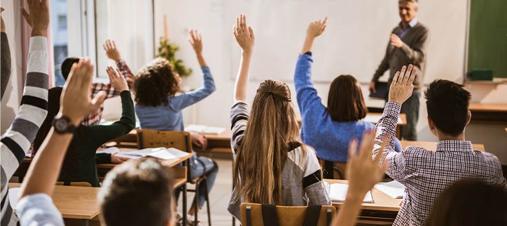 Students raise their hands to answer a question. Your company could offer tuition assistance as a fringe benefit.