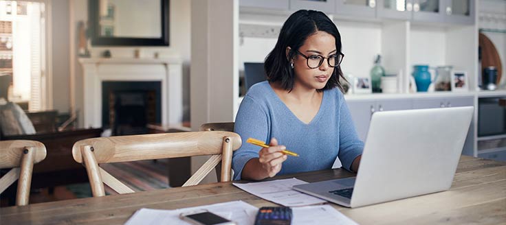 A woman works on her laptop, possibly applying for jobs. Offering fringe benefits can make your company more appealing to potential hires.