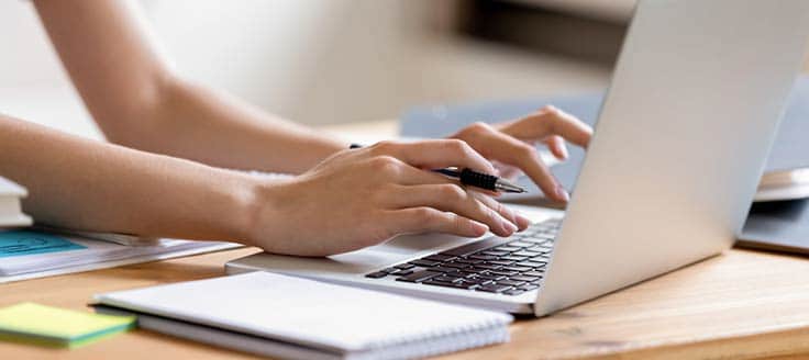 A woman types on her laptop as she works from home during the coronavirus outbreak