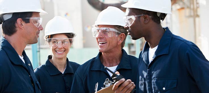 Uniformed workers wear protective goggles and hard hats while out at a job site.