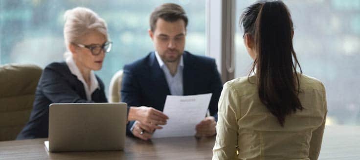 Business people review a job applicant's resume during her interview.